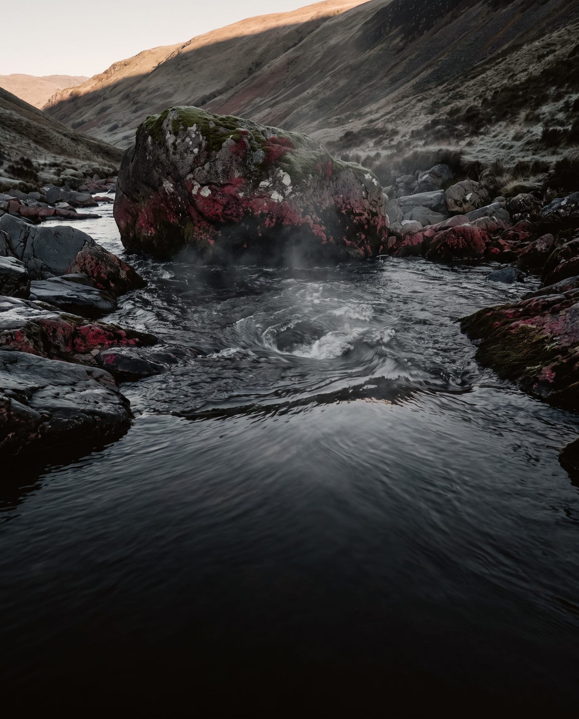 Gebirgsbach im ersten Morgenlicht, dessen Wasser sich zu einem Wirbel dreht